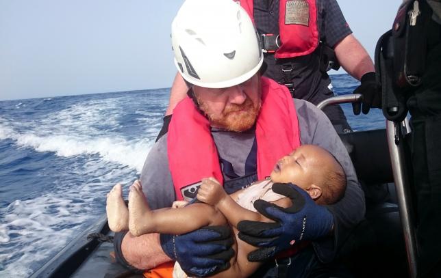A German rescuer from the humanitarian organisation Sea-Watch holds drowned migrant baby of the Libyan cost